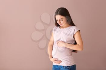 Beautiful pregnant woman on color background�