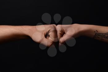 Man and woman making fist bump gesture on dark background�