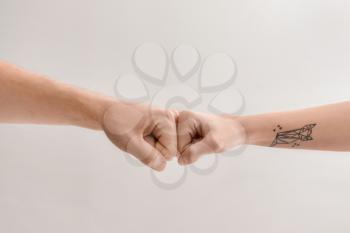 Man and woman making fist bump gesture on light background�