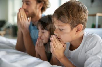 Family praying near bed at home�