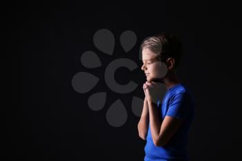 Portrait of praying boy on dark background�