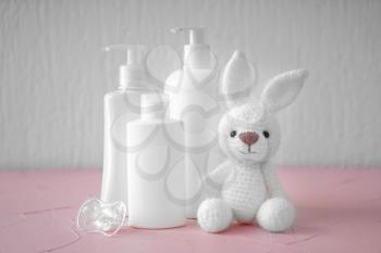 Bunny toy with pacifier and cosmetics for baby on color table�