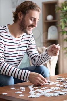 Young man doing jigsaw puzzle at home�