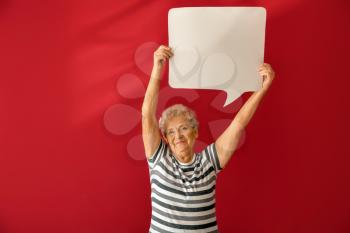Senior woman with blank speech bubble on color background�