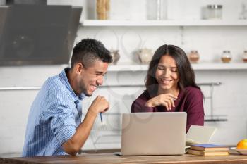 Young couple with laptop in kitchen�