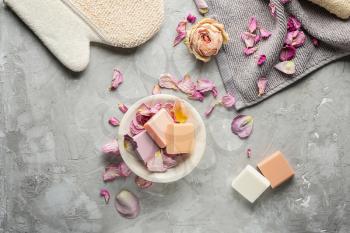 Different soap bars with rose petals on grey background�