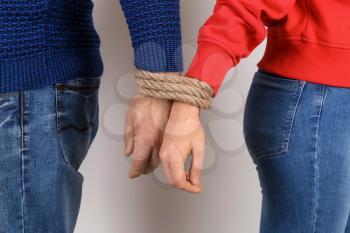 Couple with tied together hands on light background. Concept of addiction�