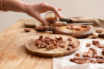 Woman preparing candied pecan nuts on table�