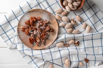 Plate with candied pecan nuts on white table�