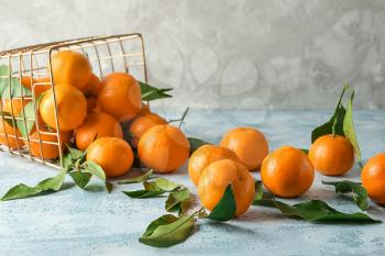 Overturned basket with tasty juicy tangerines on light table�