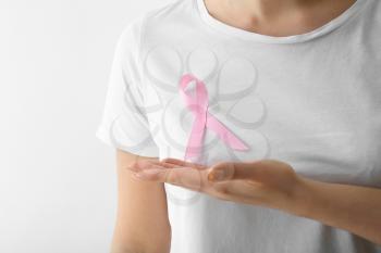 Woman with pink ribbon on light background. Breast cancer awareness concept�