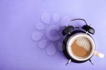 Cup of coffee and alarm clock on color background�