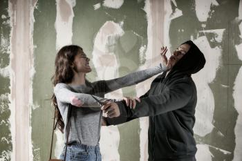 Young woman defending herself from attack by thief on color background�