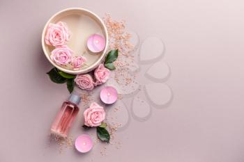 Spa composition with candles, flowers and essential oil on light background�