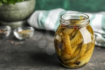 Glass jar with fermented cucumbers on grey table�