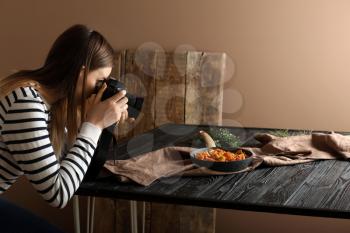 Young woman taking picture of food in professional studio�