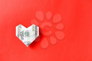 Origami heart made of dollar banknote on color background�