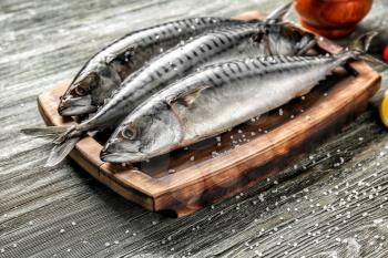 Board with tasty raw mackerel fish on wooden table�