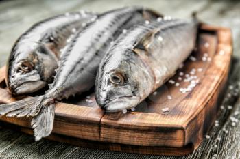Wooden board with tasty raw mackerel fish on table�