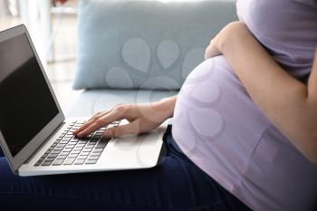 Beautiful pregnant woman using laptop at home, closeup�