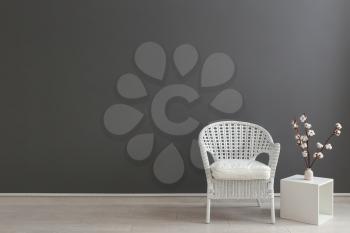 Comfortable armchair and shelf unit near grey wall�