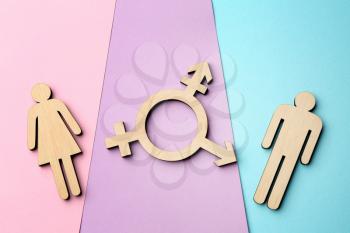 Female and male figures with symbol of transgender on color background�