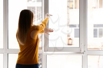 Young woman opening window in flat�