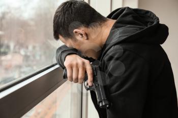 Young man with gun going to commit suicide near window�