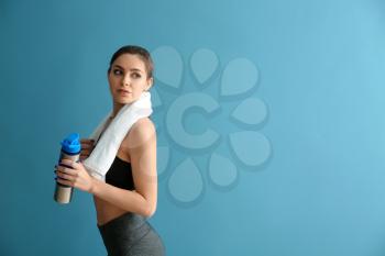Sporty young woman with bottle of water on color background�