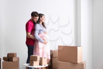 Happy pregnant couple with belongings at new home�