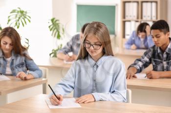 Pupils passing school test in classroom�