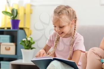 Little girl reading book at speech therapist office�