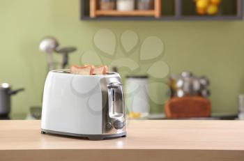 Toaster with bread slices on table�