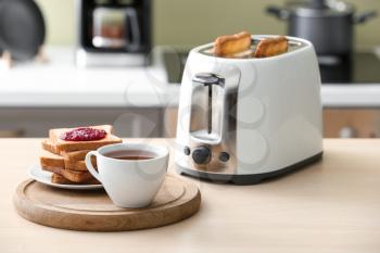 Toaster with bread slices and cup of coffee on table�