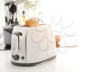 Toaster with bread slices on kitchen table�