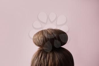 Young woman with hair bun on color background�
