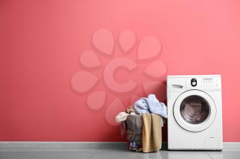 Modern washing machine and laundry near color wall�
