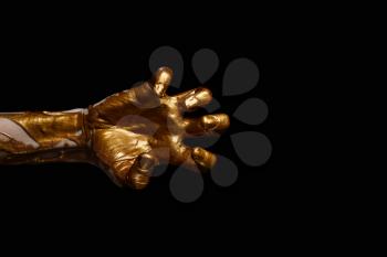 Female hand with golden paint against dark background�