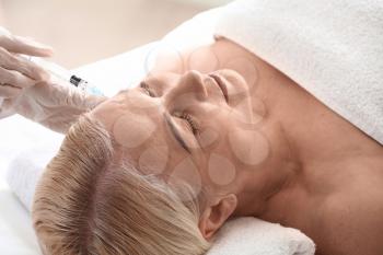 Mature woman receiving filler injection in beauty salon�