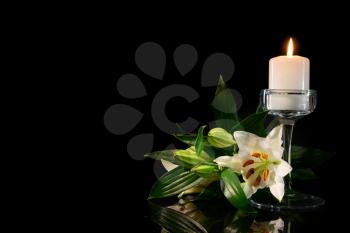 Burning candle and flowers on black background�