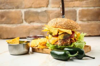 Tasty burger with nachos and guacamole on table�