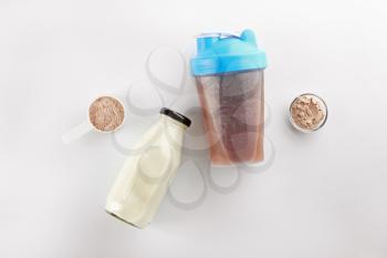 Bottles of protein shake and milk on white background�
