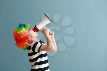 Little boy in funny disguise and with megaphone on color background. April fools' day celebration�