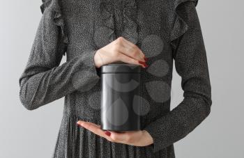 Woman with mortuary urn on light background�