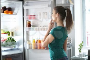 Woman standing near open fridge at home�