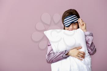 Sleepy woman with mask and pillow on color background�