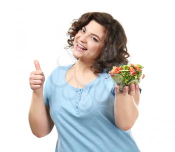 Overweight woman with bowl of salad showing thumb-up on white background. Weight loss concept�