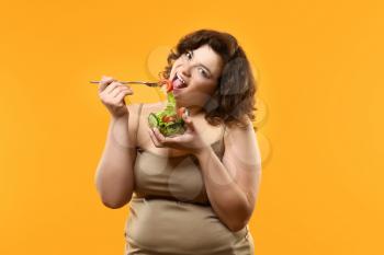 Overweight woman with salad on color background. Weight loss concept�