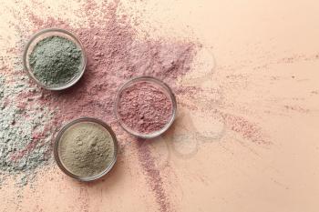 Cosmetic clays in bowls on color background�