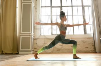 Sporty African-American woman practicing yoga indoors�